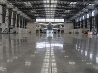 an image of a large hangar with two planes inside it or in the building on one side, and others standing outside