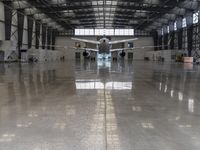 an image of a large hangar with two planes inside it or in the building on one side, and others standing outside