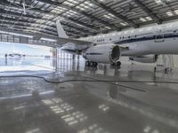 a white plane parked inside of a hanger in an hanger with an ocean