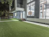 the outside of an apartment that has artificial grass and artificial lighting on it's side