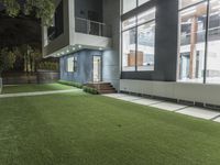 the outside of an apartment that has artificial grass and artificial lighting on it's side