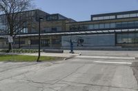 the large building is empty and the parking lot has no vehicles in it and trees with no leaves