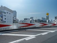 a white and red traffic guard at an intersection and next to a city with buildings in the background