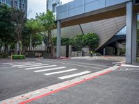 a empty street with a red curb on each side of it with an unusual modern building behind it