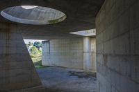 a tunnel with concrete walls and an open circular window for the sun to shine down on