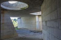 a tunnel with concrete walls and an open circular window for the sun to shine down on