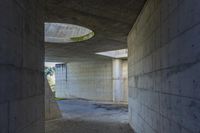 a tunnel with concrete walls and an open circular window for the sun to shine down on