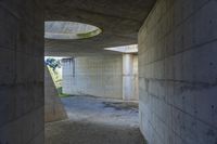 a tunnel with concrete walls and an open circular window for the sun to shine down on