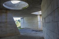 a tunnel with concrete walls and an open circular window for the sun to shine down on