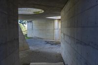 a tunnel with concrete walls and an open circular window for the sun to shine down on