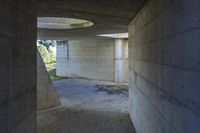 a tunnel with concrete walls and an open circular window for the sun to shine down on