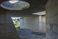 a tunnel with concrete walls and an open circular window for the sun to shine down on