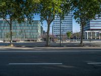 an empty street in front of a building and trees on the other side of the road