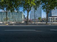 an empty street in front of a building and trees on the other side of the road