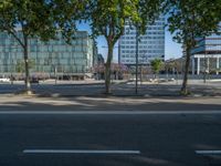 an empty street in front of a building and trees on the other side of the road