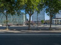 an empty street in front of a building and trees on the other side of the road