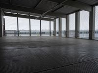 an industrial space with a very large window looking out to the sea and some cars in the lot