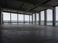 an industrial space with a very large window looking out to the sea and some cars in the lot