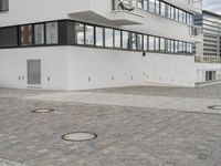 an empty courtyard in front of white buildings with windows and a fire hydrant on it