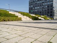 a man riding on top of a skateboard on a stone road near tall buildings