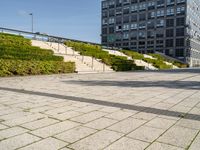 a man riding on top of a skateboard on a stone road near tall buildings