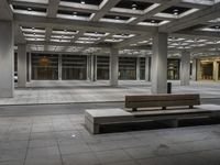 a empty concrete and steel patio in the middle of a city square with lights and columns