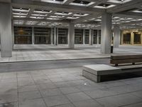 a empty concrete and steel patio in the middle of a city square with lights and columns