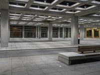 a empty concrete and steel patio in the middle of a city square with lights and columns