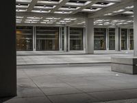 a empty concrete and steel patio in the middle of a city square with lights and columns