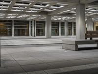 a empty concrete and steel patio in the middle of a city square with lights and columns