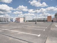 this is an empty parking lot with several buildings in the background and many streetlights