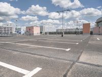 this is an empty parking lot with several buildings in the background and many streetlights