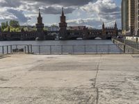 a person sitting on a bench looking out at the water with a bridge in front of it