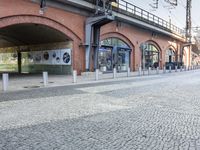 a red bricked walkway and some buildings and street lamps and a street sign hanging from the side of the building