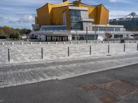 a long walkway leads to a colorful building that has a lot of yellow windows and glass