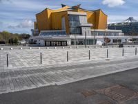 a long walkway leads to a colorful building that has a lot of yellow windows and glass