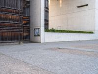 a red fire hydrant sitting next to a building and door way with planters and wooden paneled wall