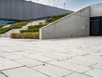 a photo of a skateboarder in a concrete parking lot with stairs and landscaping