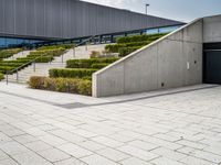 a photo of a skateboarder in a concrete parking lot with stairs and landscaping