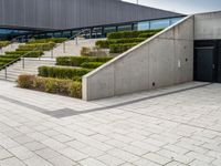 a photo of a skateboarder in a concrete parking lot with stairs and landscaping