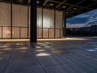 a sidewalk with a window and some lights outside it at dusk by a clock tower