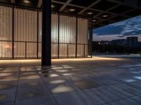 a sidewalk with a window and some lights outside it at dusk by a clock tower