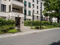 a long building with an apartment and trees on the other side of it on the sidewalk