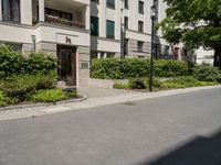 a long building with an apartment and trees on the other side of it on the sidewalk