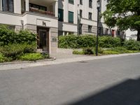 a long building with an apartment and trees on the other side of it on the sidewalk