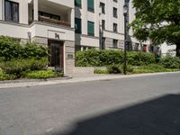 a long building with an apartment and trees on the other side of it on the sidewalk