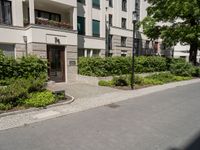 a long building with an apartment and trees on the other side of it on the sidewalk