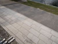 a paved sidewalk along the bank next to some water and benches and trees in the shade