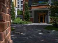 a residential driveway with a bench and bushes in between buildings and green grass on either side