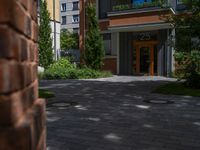 a residential driveway with a bench and bushes in between buildings and green grass on either side